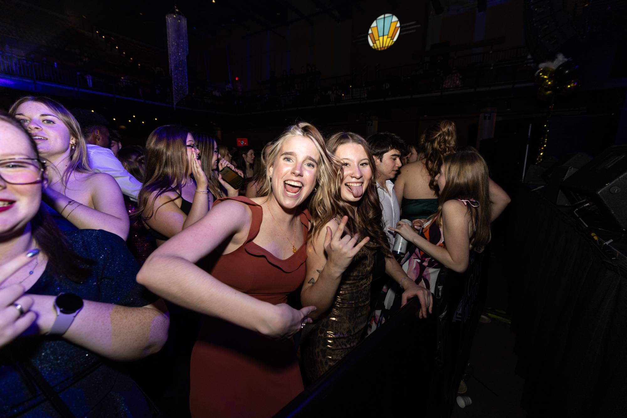 girls standing at formal dance smiling and dancing in formal dresses